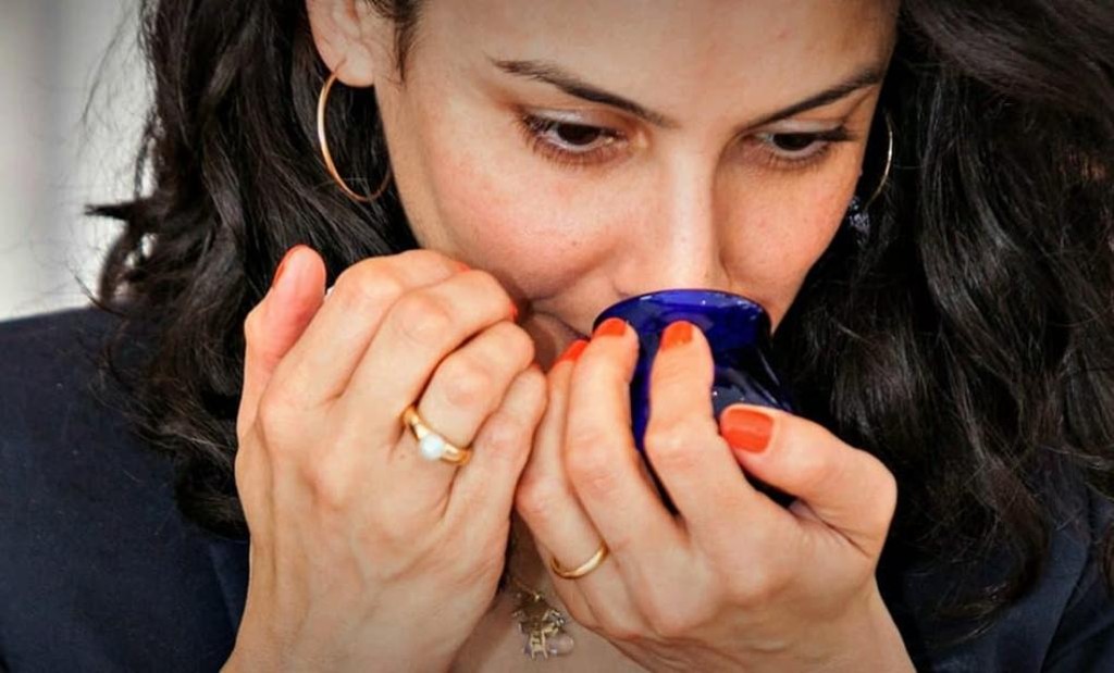 A woman performs olfactory analysis of olive oil